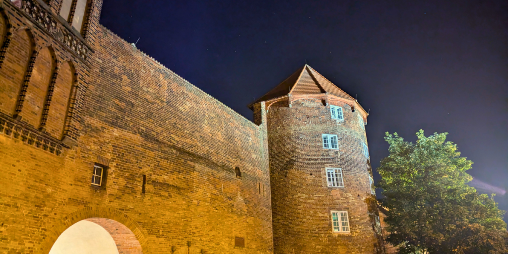 Nahaufnahme des beleuchteten Burgtors bei Nacht, in der Lübecker Altstadt