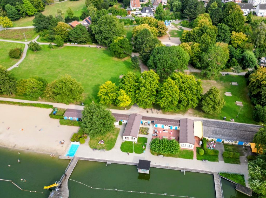 Luftbild zeigt Drägerpark Lübeck mit Grill- und Bolzwiese, anteilig Spieplatz, Naturbad Marli mit Sandstrand, aufgenommen über der Wakenitz