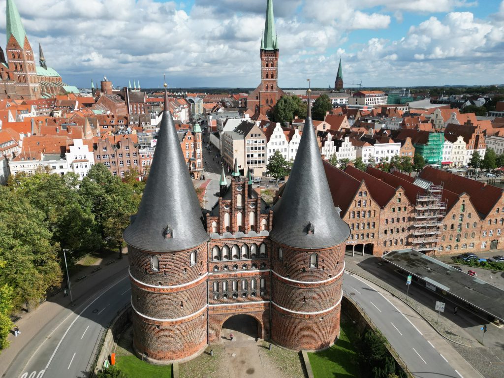 Luftbild zeigt das Lübecker Holstentor und die Lübecker Altstadt mit Petrikirche, Aegidienkirche, Marienkirche und historischen Speicher, aufgenommen über dem Holstentorplatz
