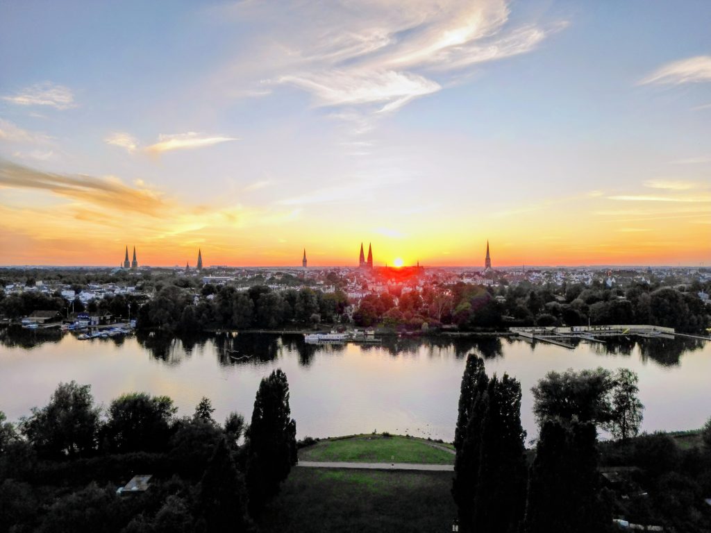 Luftbild von wunderschönem Sonnenuntergang hinter Lübecker Altstadt, Wakenitz und Falkenwiese beim Tor der Hoffnung aufgenommen
